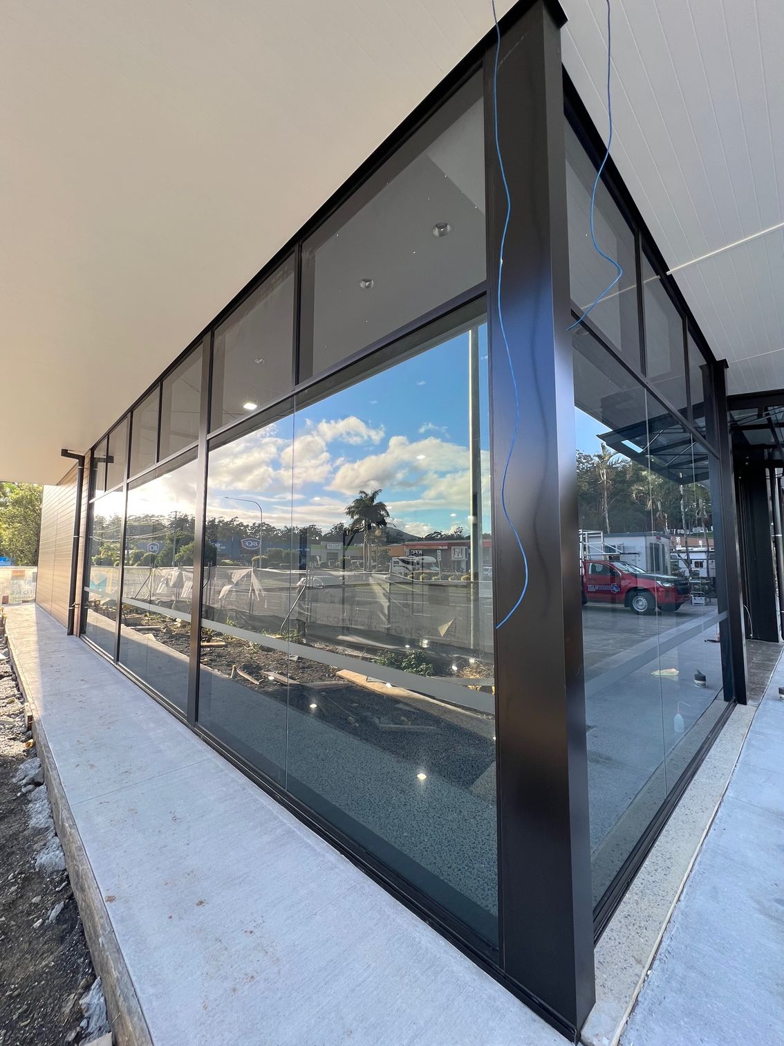 A Building With a Lot of Windows and a Reflection of Cars in the Windows — Rooney Glass in Coffs Harbour, NSW