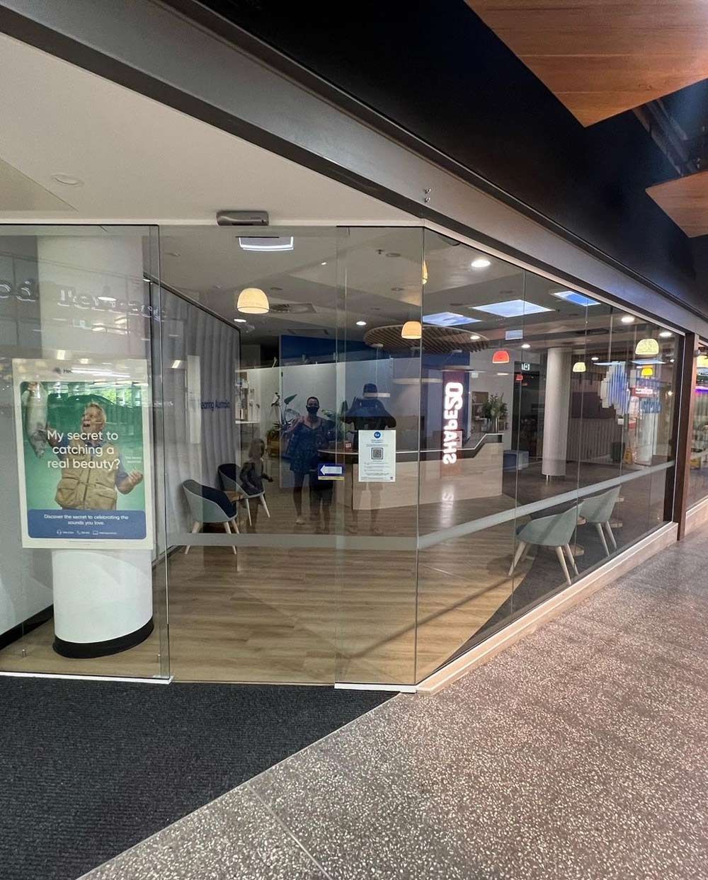 A Store Front With A Glass Door And A Poster On The Wall — Rooney Glass in Coffs Harbour, NSW