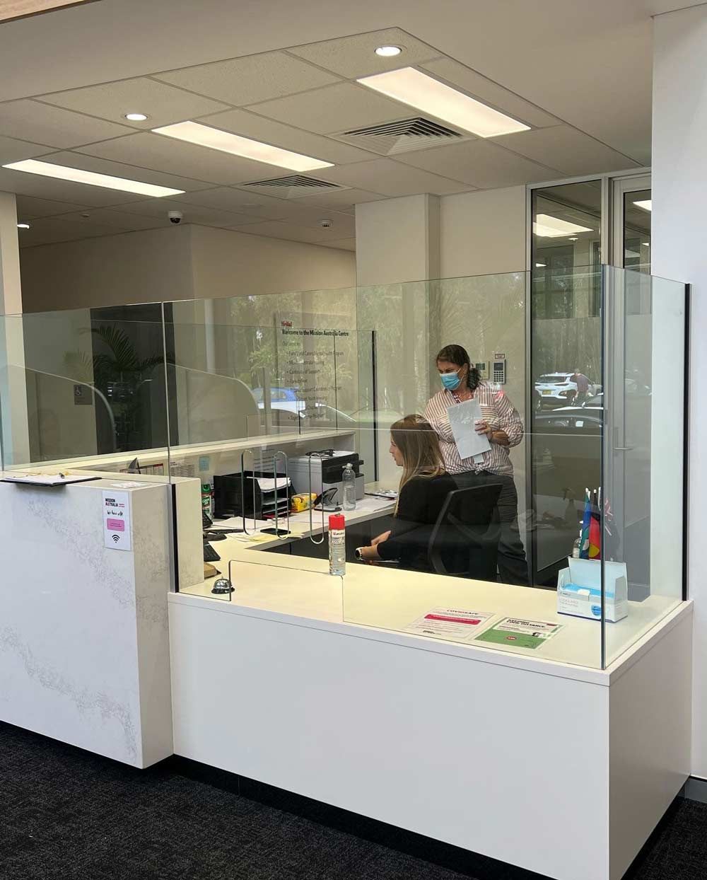 A Woman Wearing A Mask Is Standing Behind A Counter — Rooney Glass in Coffs Harbour, NSW