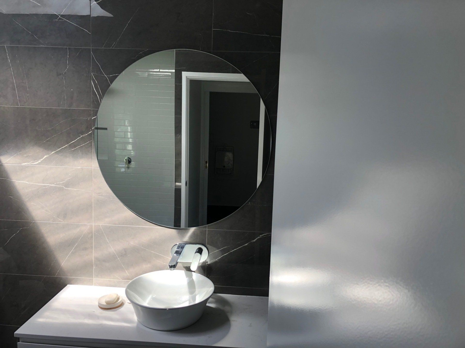 A Bathroom With a Sink and a Round Mirror — Rooney Glass in Coffs Harbour, NSW