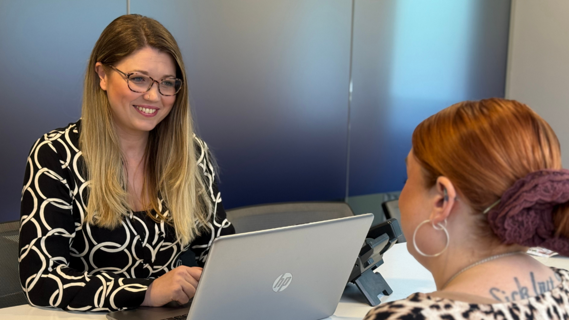Man in suit gestures while speaking to another man with dreadlocks in a consultation room.