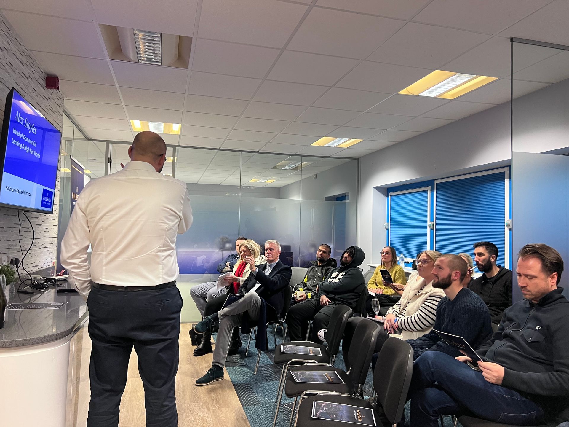 A man presents to a seated audience in a modern office.