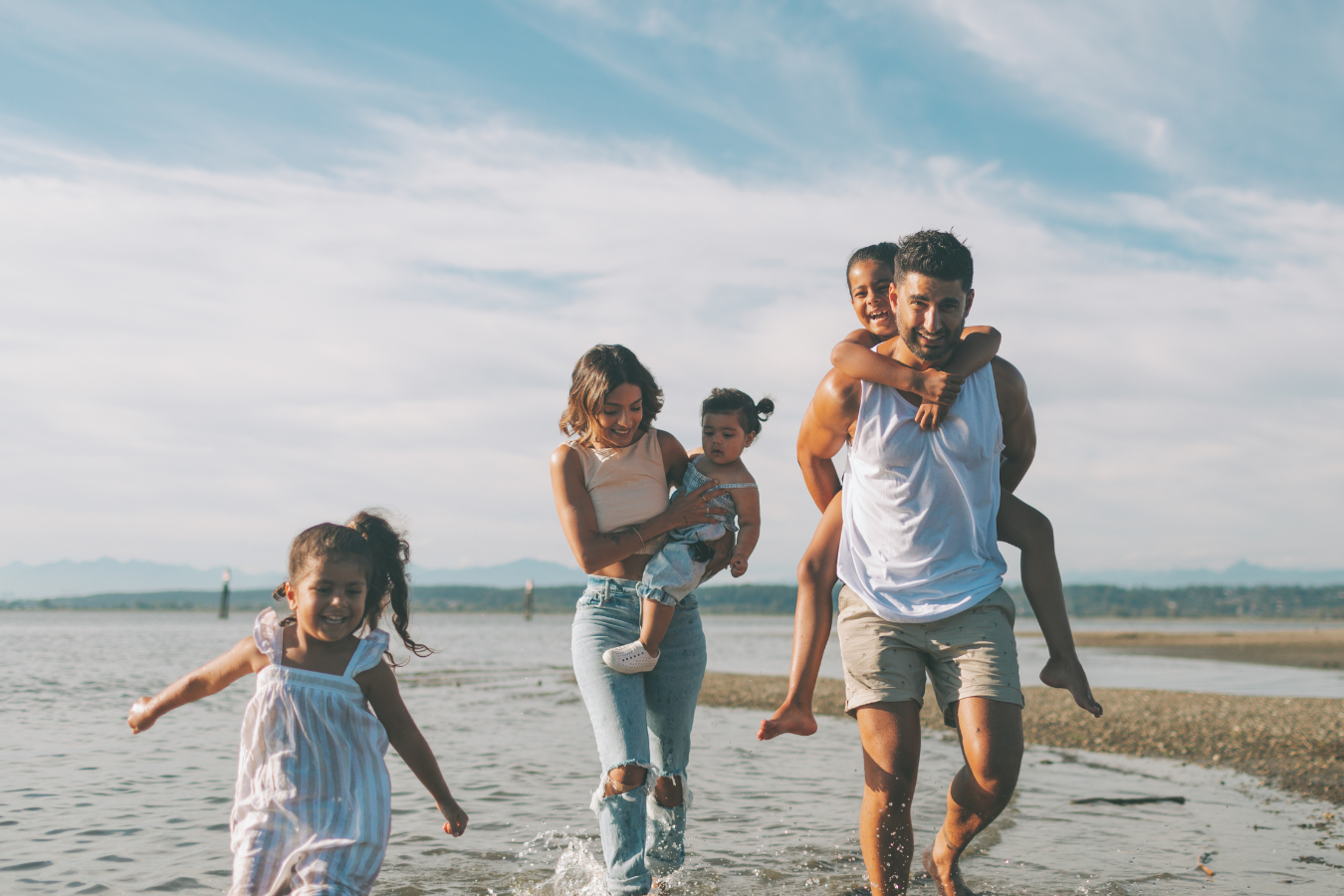 Family of six playing in the water at the beach on a sunny day.