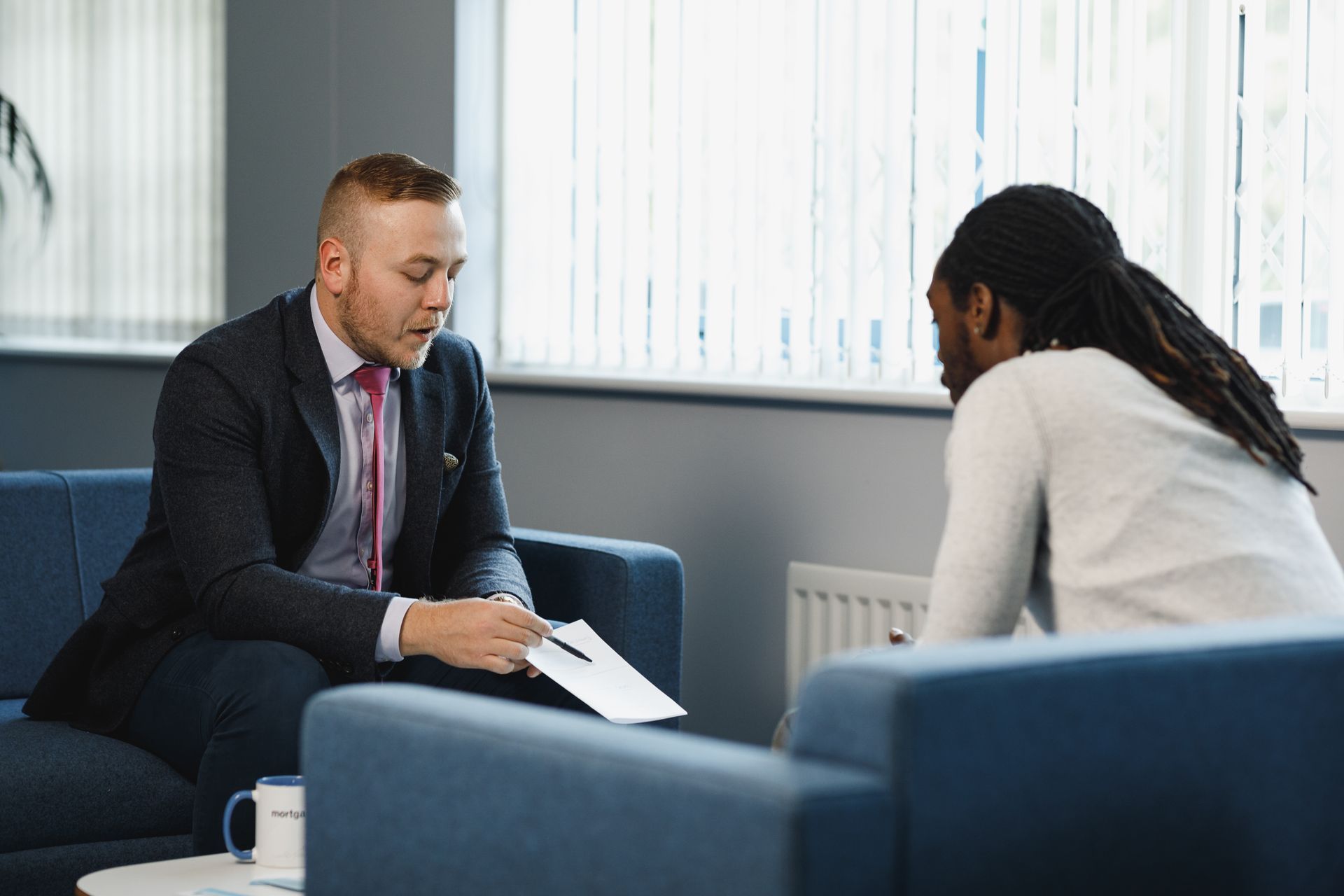 Four diverse professionals collaborate around a table, smiling, with papers and laptops in a bright office setting.