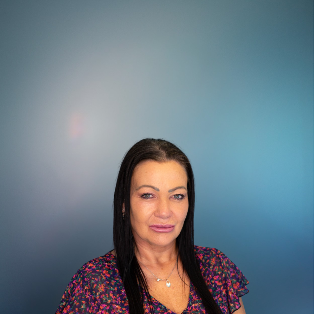 Woman with dark hair and floral top against a blue gradient background.