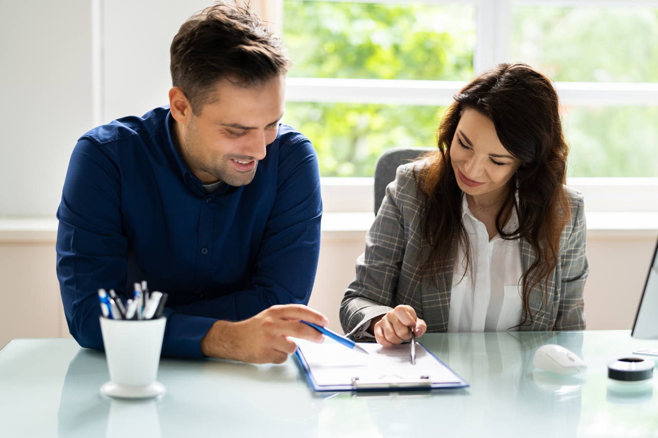 Man and woman reviewing paperwork at a desk; both looking at the document, smiling.