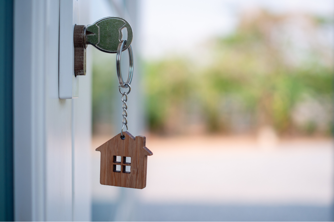 Key in a door lock with a house-shaped keychain.