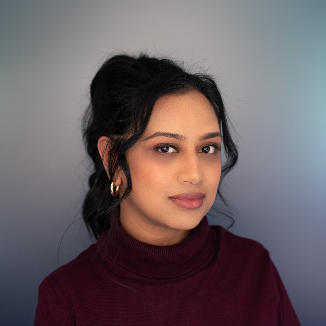 Woman with dark hair in a burgundy turtleneck, wearing hoop earrings, looking at the camera.