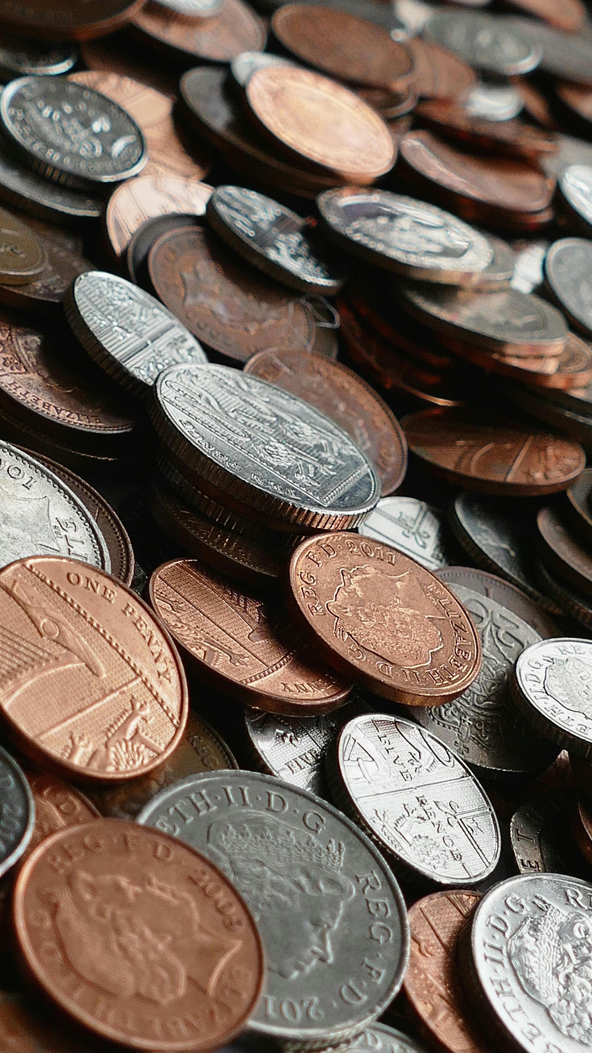 Pile of mixed coins: copper pennies, silver quarters, and dimes.