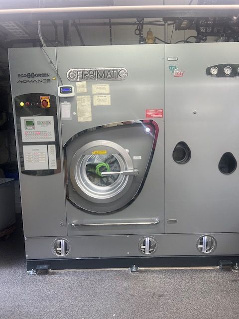 A large washing machine is sitting on the floor in a room.