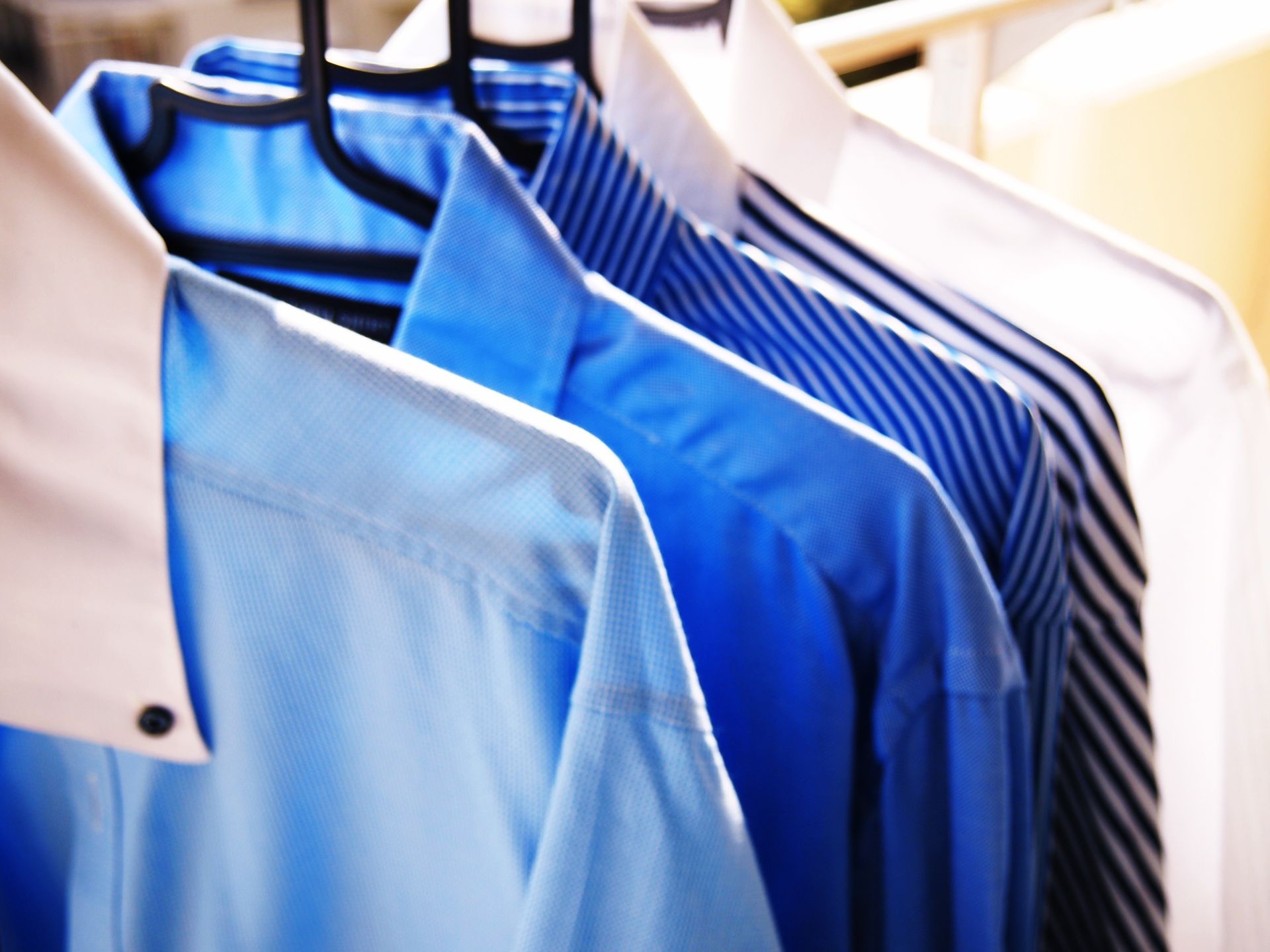 A row of blue and white shirts hanging on a rack