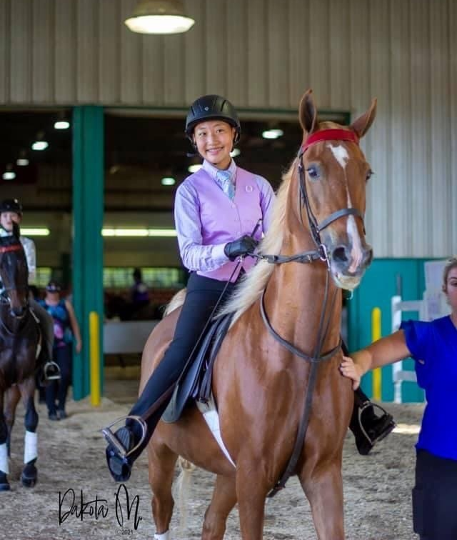 photo of smiling Lenux Stables academy rider sitting on horse following horse show class