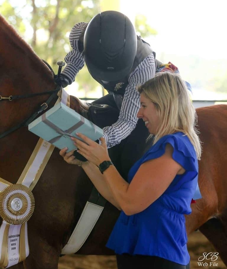 photo of Lenux Stables academy rider and instructor looking at prize after winning horse show class