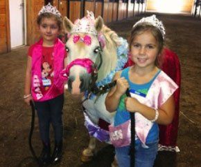 photo of two young girls wearing birthday crowns next to white miniature horse