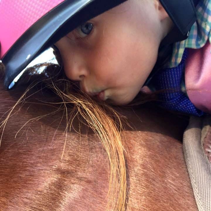 photo of girl at horse show, kissing horse on neck