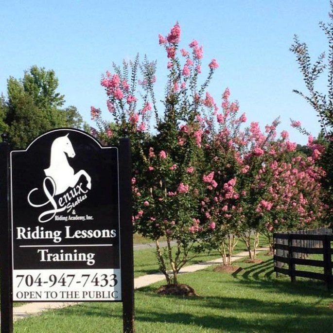 photo of Lenux Stables entrance sign with beautiful blooming trees and rail fence in background