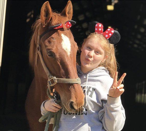 photo of girl wearing Minnie Mouse ears and polka-dot hair ribbon holding American Saddlebred horse named 
