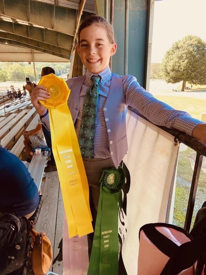 photo of Lenux Stables academy rider displaying her ribbons at horse show