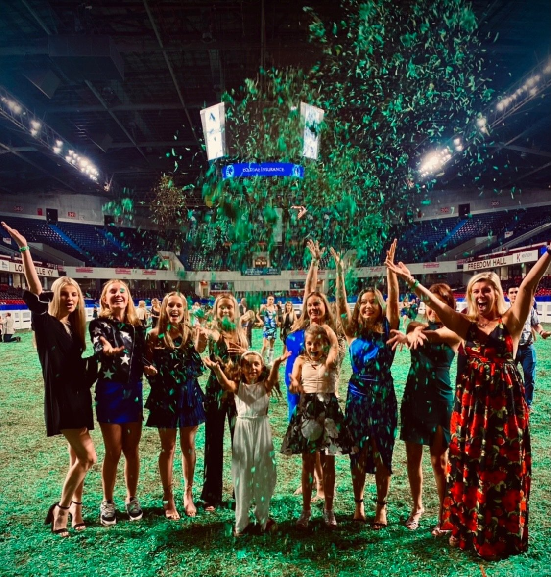 photo of Lenux Stables riders and instructors tossing green shavings into air in ring at World's Championship Horse Show