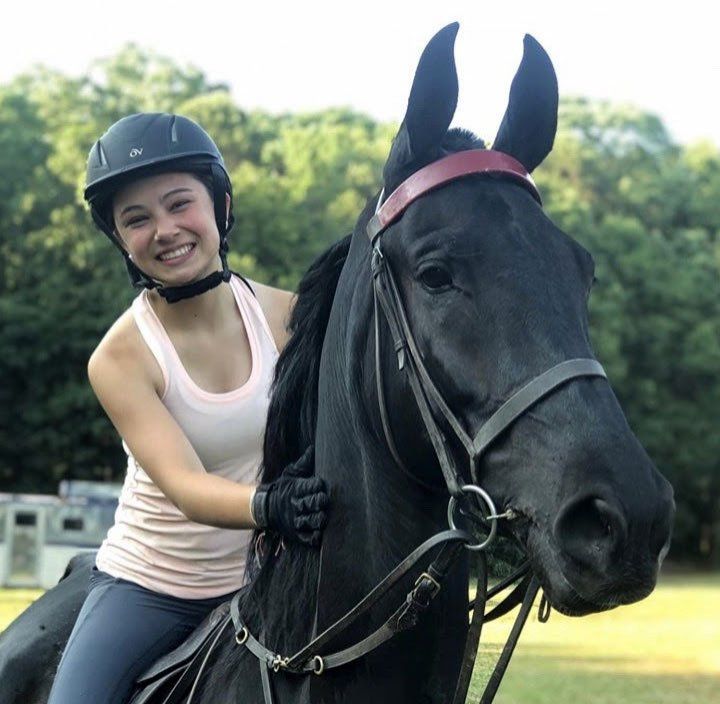 photo of smiling girl sitting on black American Saddlebred horse named 