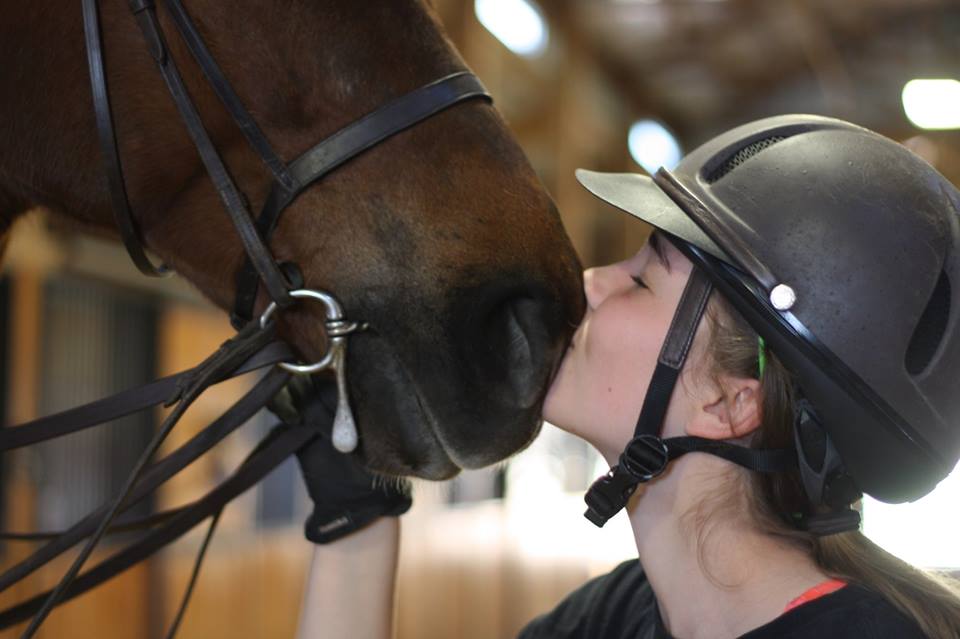 photo of girl kissing horse on its muzzle