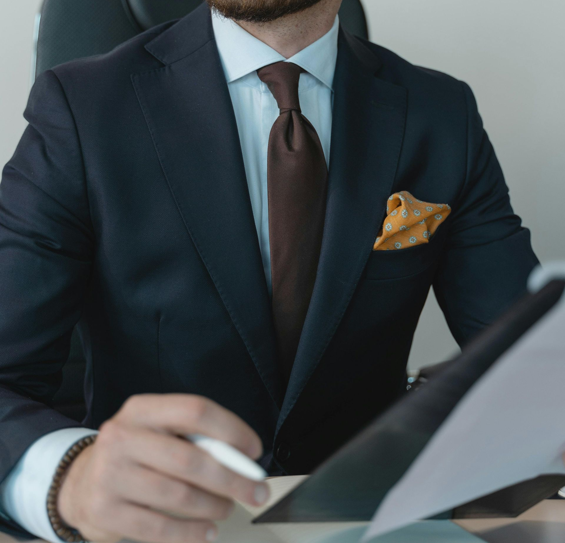 Due persone in abiti professionali si stringono la mano sullo sfondo sfocato di una città.