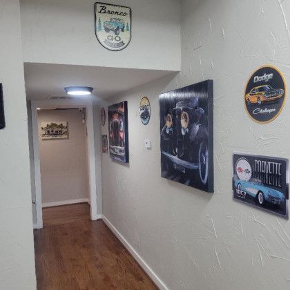 A hallway with a lot of pictures of cars on the wall.