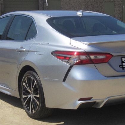 A silver car with a license plate that has the letter b on it