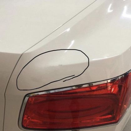 A close up of a white car with a red tail light.