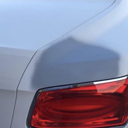 A close up of a silver car with a red tail light