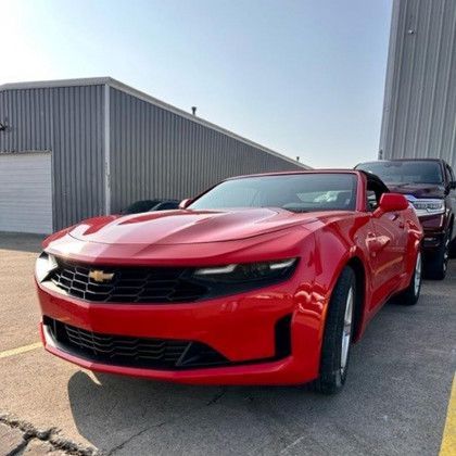 A red chevrolet camaro is parked in a parking lot.