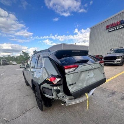 A damaged toyota rav4 is parked in a parking lot.