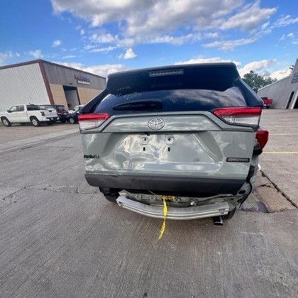 A damaged toyota rav4 is parked in a parking lot.