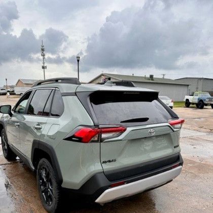 A toyota rav4 is parked in a parking lot on a rainy day.