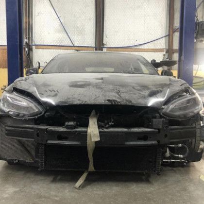 A black car is sitting on a lift in a garage.