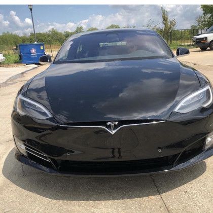 A black tesla model s is parked in a parking lot.