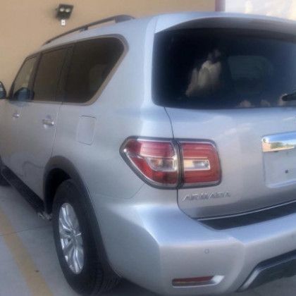 A silver nissan patrol is parked in a parking lot
