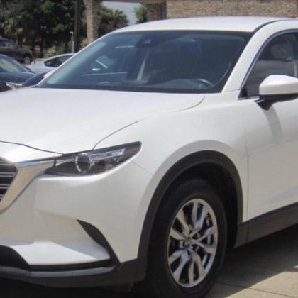 A white car is parked in front of a building