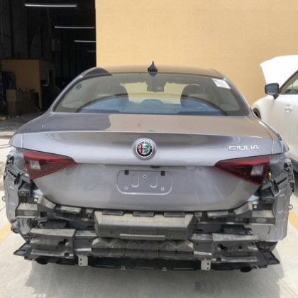 A gray alfa romeo car is being dismantled in a garage