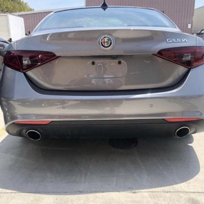 A gray alfa romeo giulia is parked in a parking lot.