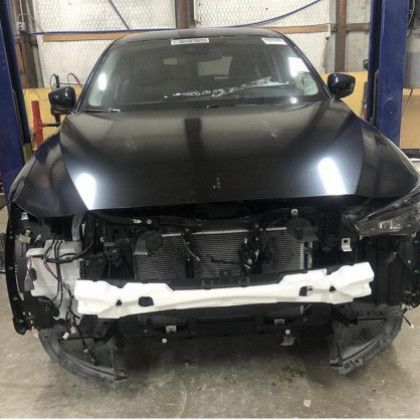 A black car is sitting on a lift in a garage.