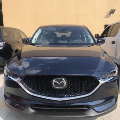 A black mazda cx 5 is parked in front of a building.
