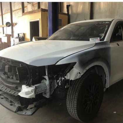 A white car is sitting on a lift in a garage.