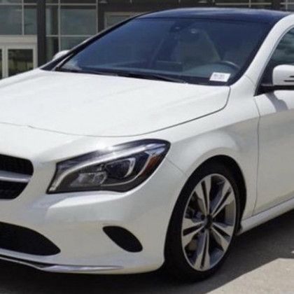 A white car is parked in front of a building.