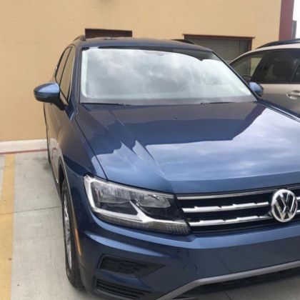 A blue volkswagen is parked in front of a building
