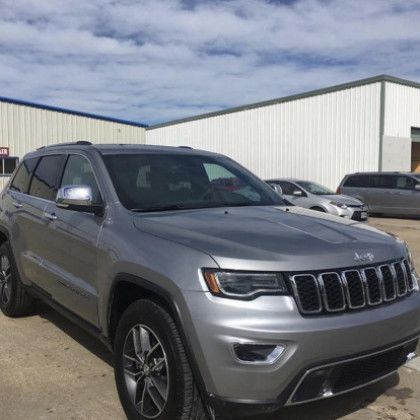 A silver jeep grand cherokee is parked in a parking lot.