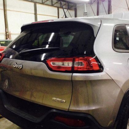 A silver jeep is parked in a garage.