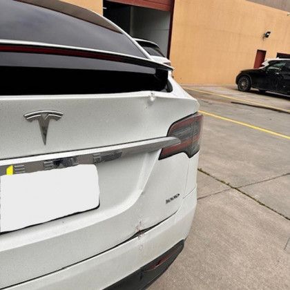 A white tesla model x is parked in a parking lot.