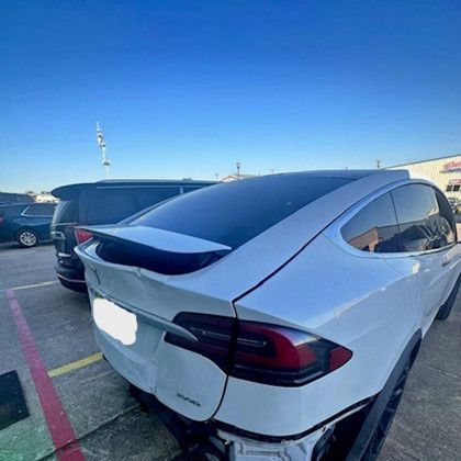 A white tesla model x is parked in a parking lot.
