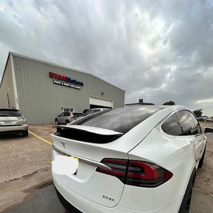 A white tesla model x is parked in front of a building.
